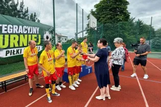 Uczestnicy turnieju piłkarskiego odbierają nagrody na boisku.