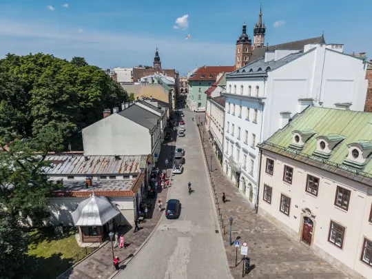 Ulica z widokiem na zabytkowe budynki i zieleń w Krakowie.