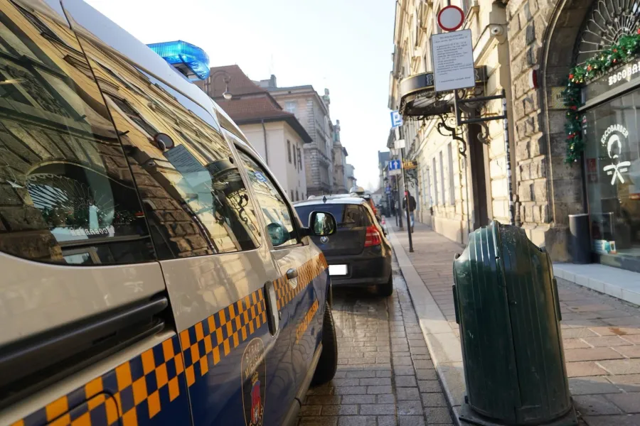 Radiowóz policyjny na ulicy z widocznymi budynkami i znakami drogowymi.