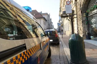Radiowóz policyjny na ulicy z widocznymi budynkami i znakami drogowymi.