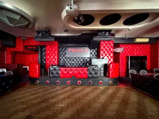 Czerwono-czarna scena z barowym wystrojem, z miejscami do siedzenia i oświetleniem.