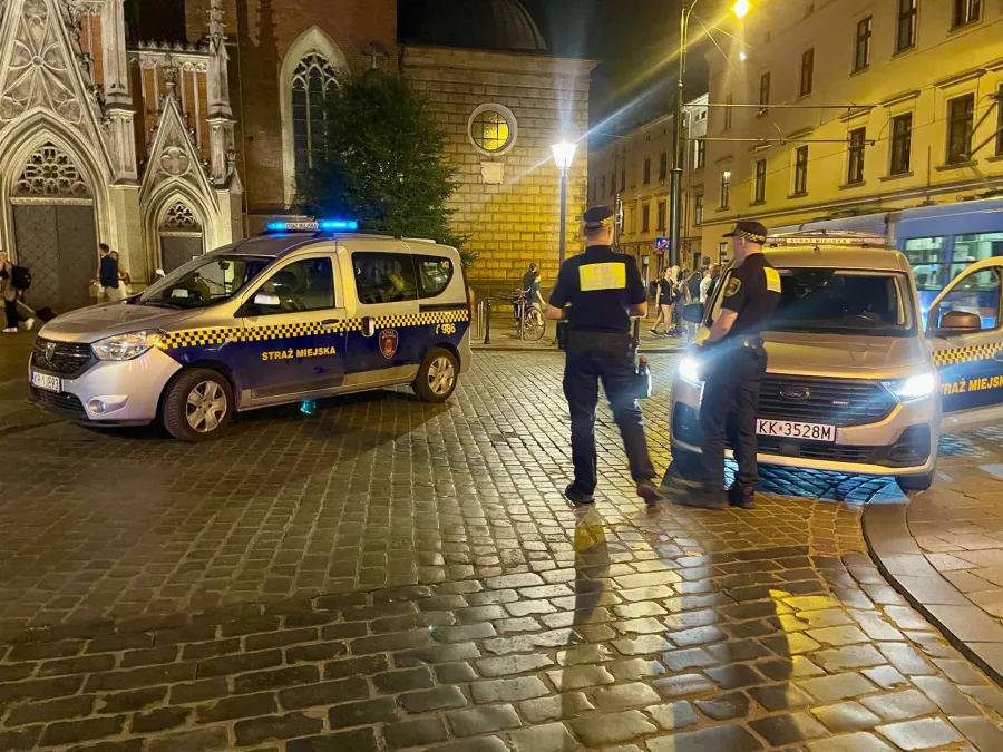 Interwencja straży miejskiej w miejskim otoczeniu nocą.