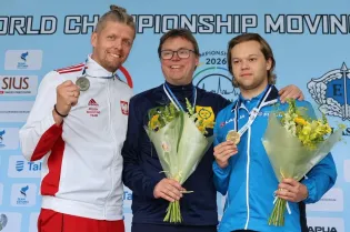 Trzej mężczyźni z medalami i bukietami kwiatów na podium mistrzostw świata.