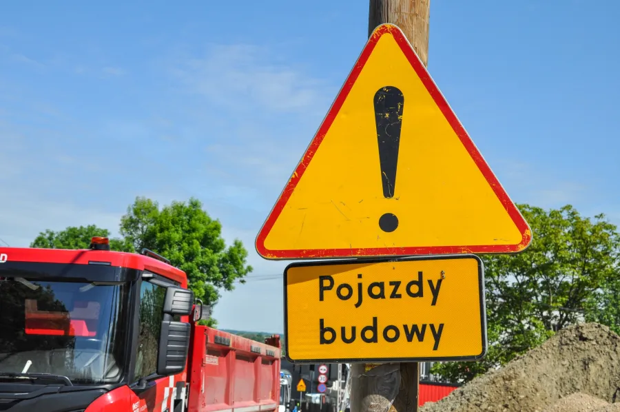 Żółty znak ostrzegawczy z napisem Pojazdy budowy.