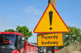 Żółty znak ostrzegawczy z napisem Pojazdy budowy.