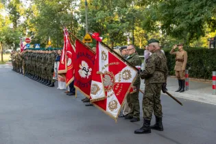 Ceremonia wojskowa z żołnierzami i sztandarami.