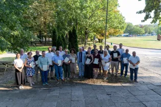 Grupa ludzi pozująca z dyplomami w parku.