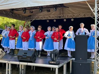 Grupa dzieci w tradycyjnych strojach śpiewa na scenie podczas występu.