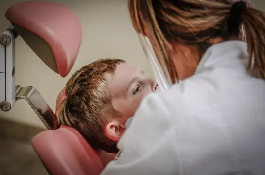 Dziecko siedzące na fotelu dentystycznym podczas wizyty u stomatologa.