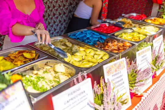 Stoiska z różnorodnymi pierogami w kolorowych pojemnikach.