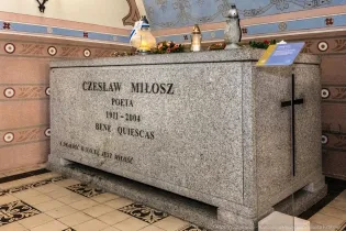 Grób Czesława Miłosza z inskrypcją i zniczami.