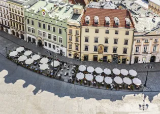 Kawiarniane parasole na rynku, otoczone kolorowymi budynkami.