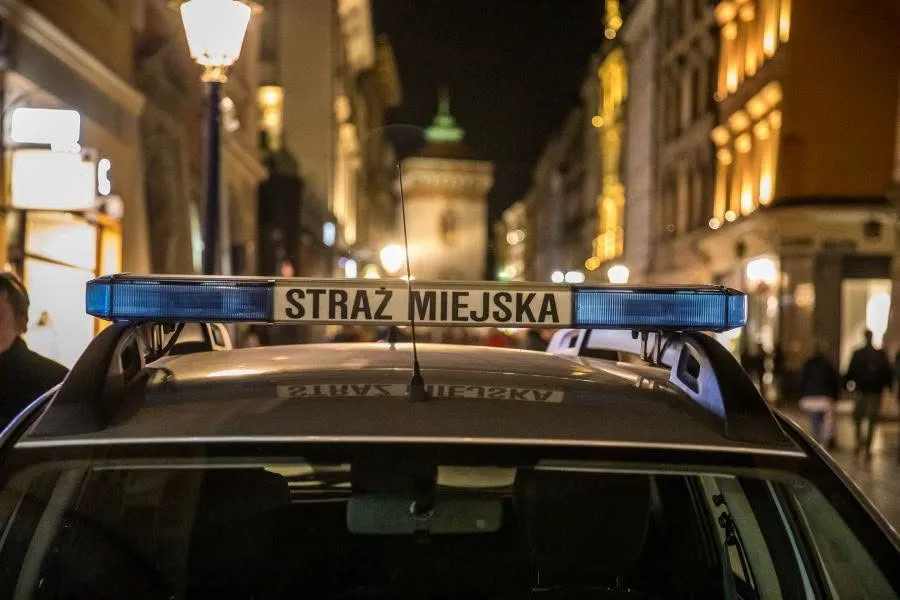 Radiowóz straży miejskiej z niebieskim światłem w nocy.