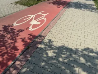 Ścieżka rowerowa obok chodnika, z wyraźnym symbolem roweru.