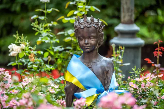 Pomnik Księżniczki Kijowskiej Anny Jarosławówny, ozdobiony niebiesko-żółtą wstęgą, otoczony różowymi kwiatami.
