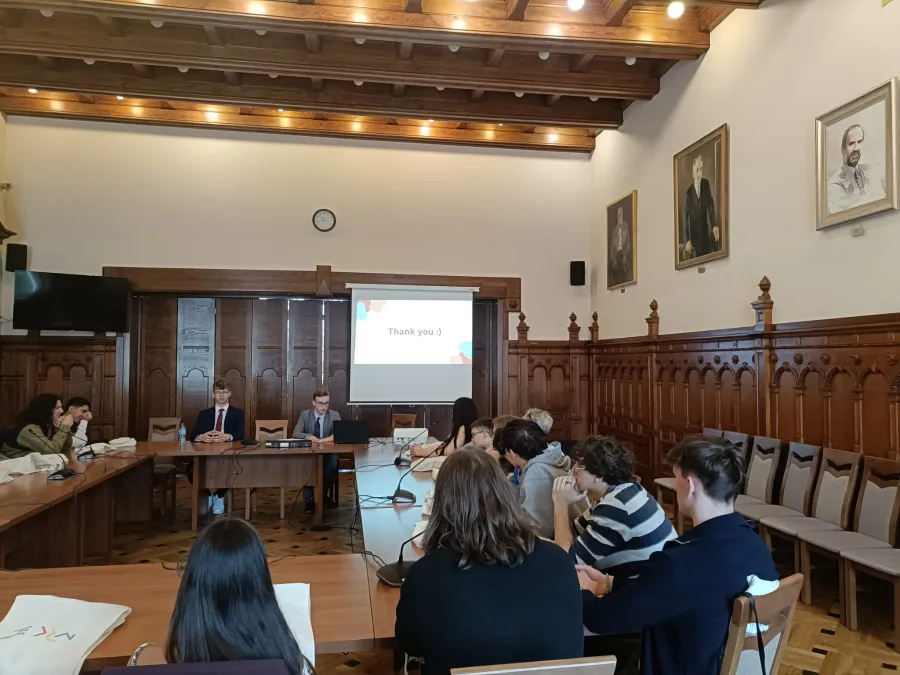 Spotkanie w sali konferencyjnej z prezentacją na ekranie i uczestnikami siedzącymi przy stole.