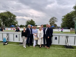 Grupa osób w eleganckich strojach na boisku sportowym.