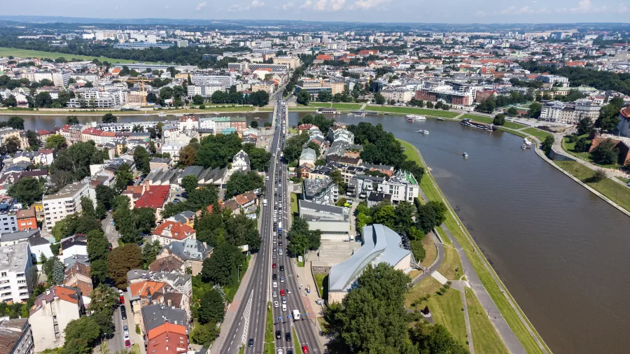 Widok na miasto z rzeką, z zabudową, drogami i zielenią w tle.
