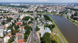 Widok na miasto z rzeką, z zabudową, drogami i zielenią w tle.