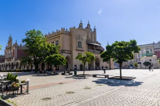 Krakowski rynek z piękną architekturą i zielonymi drzewami w słoneczny dzień.