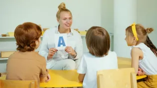 Nauczycielka pokazuje dzieciom literę A podczas zajęć edukacyjnych.