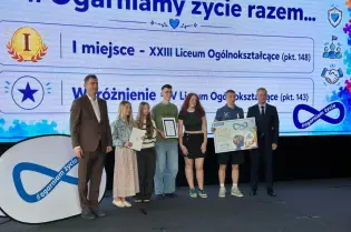Uczniowie odbierają nagrody za osiągnięcia w konkursie edukacyjnym.