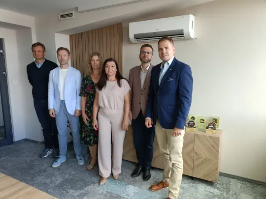Grupa sześciu osób w biurze, w formalnych strojach, stojących obok siebie.