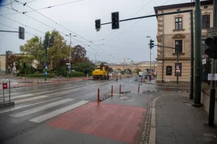 Ulica z robotami drogowymi, sygnalizacja świetlna i oznakowanie dla pieszych.