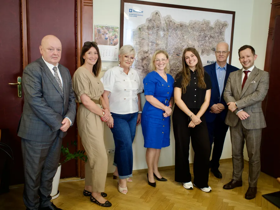 Grupa osób w formalnych strojach, pozująca do zdjęcia w biurze.