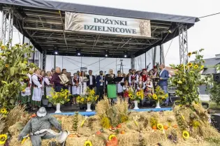 Dożynki Dzielnicowe z występami artystycznymi i dekoracjami z kwiatów oraz zboża.