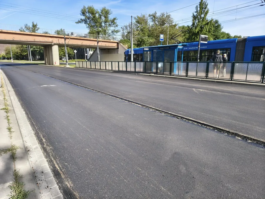 Nowa nawierzchnia drogi z przystankiem tramwajowym w tle.