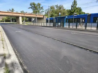 Nowa nawierzchnia drogi z przystankiem tramwajowym w tle.