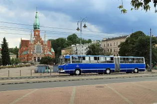 Stary niebieski autobus na tle zabytkowego kościoła i miejskiej architektury.