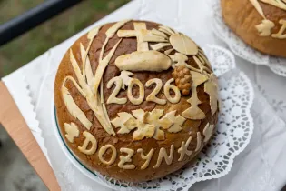 Chleb dożynkowy z dekoracjami i napisem 2020 oraz symbolami rolniczymi.