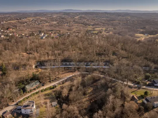 Widok na zalesiony krajobraz z domami i drogami w dolinie.