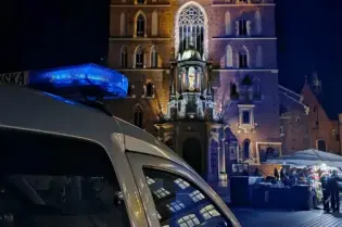 Krakowska wieża Kościoła Mariackiego nocą z radiowozem w pierwszym planie.