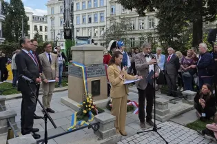 Przed cokołem na którym posadowiony jest pomnik upamiętniający księcia Józefa Poniatowskiego stoi Dyrektor Muzeum Krakowa Michał Niezabitowski i przemawia do zgromadzonych wokoło kilkunastu osób.   