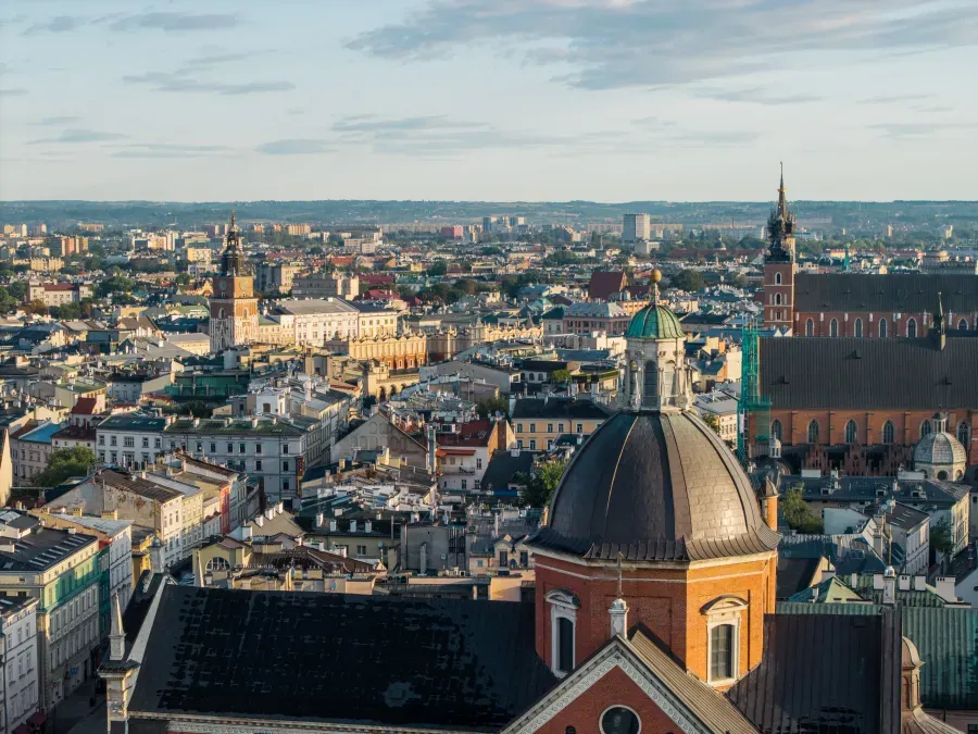 Widok na miasto z charakterystycznymi budynkami i dachami, z górującymi wieżami kościołów.