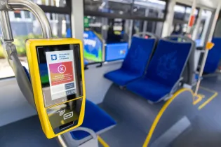 Wyświetlacz informacji w autobusie z komunikatem o czasie przyjazdu i statusie. Puste siedzenia.