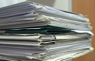Stos papierów i dokumentów w różnych kolorach i formatach.