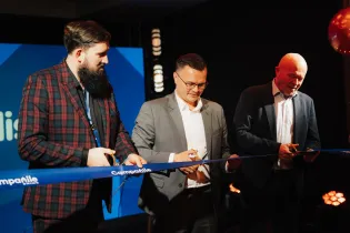 Trzech mężczyzn przecinających wstęgę podczas ceremonii otwarcia.