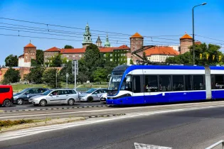 Tramwaj w Krakowie z widokiem na Wawel i ruch uliczny.