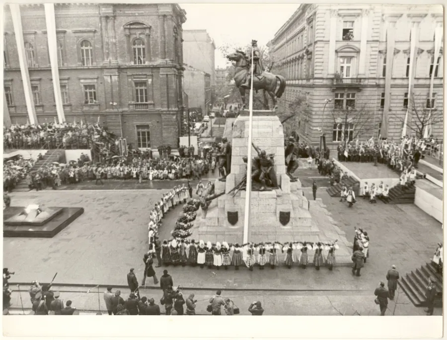 Uroczystość z udziałem tłumu ludzi wokół pomnika, z flagą na maszcie.