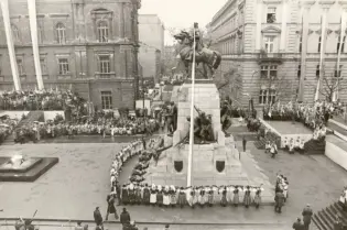 Uroczystość z udziałem tłumu ludzi wokół pomnika, z flagą na maszcie.