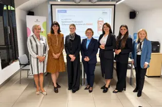 Grupa kobiet w formalnych strojach podczas spotkania w sali konferencyjnej.