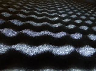 Tekstura czarnej pianki z falistym wzorem i refleksami światła.