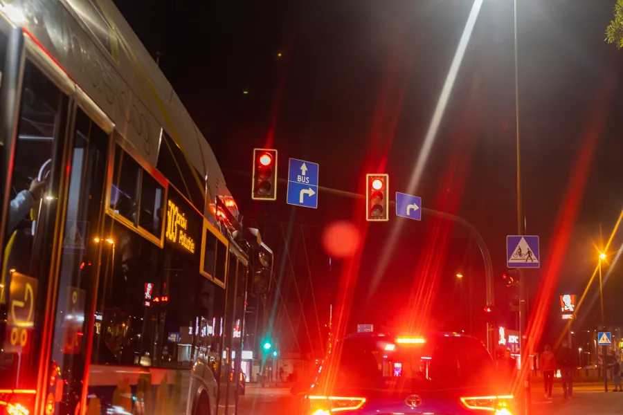 Ruch uliczny w nocy z autobusem i sygnalizacją świetlną.