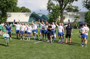Zespół rugby cieszy się po zwycięstwie, podnosząc ręce w górę na boisku.