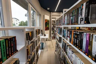 Nowoczesna biblioteka z regałami pełnymi książek i miejscem do czytania.