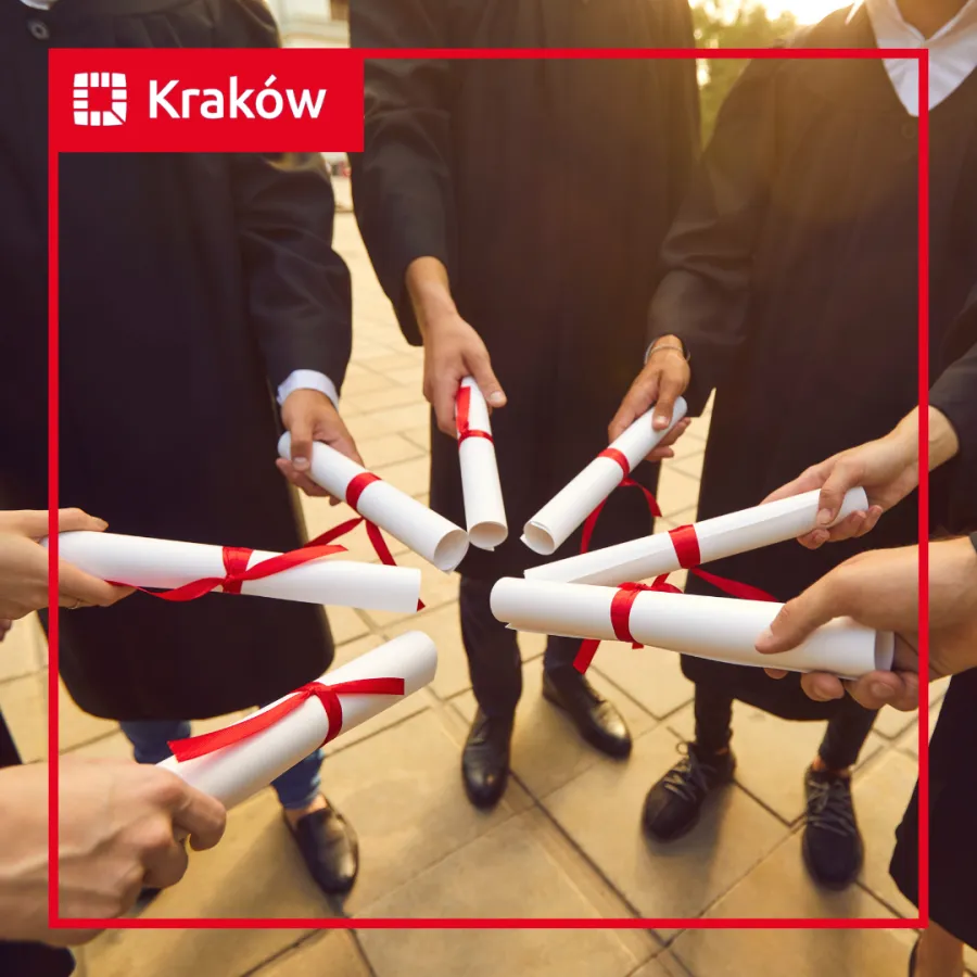 Grupa absolwentów trzymających dyplomy w rękach.